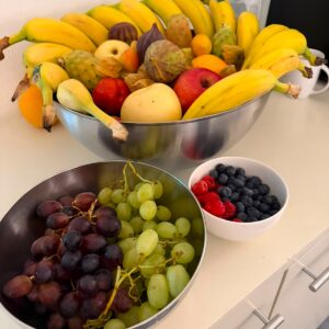Wandschild mit farbenfrohem Stillleben aus Bananen, Trauben, Beeren, Granatapfel und Feigen