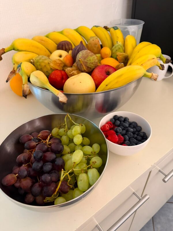 Wandschild mit farbenfrohem Stillleben aus Bananen, Trauben, Beeren, Granatapfel und Feigen
